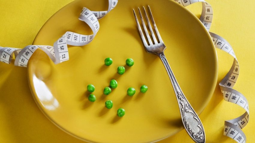Diet yellow plate with centimeter peas and fork